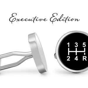 May include: A pair of silver cufflinks with a black background and a white gear shift pattern. The cufflinks feature the numbers 1, 2, 3, 4, 5, and R.