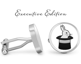 May include: A pair of silver cufflinks with a white rabbit in a black top hat design. The cufflinks are labeled "Executive Edition".