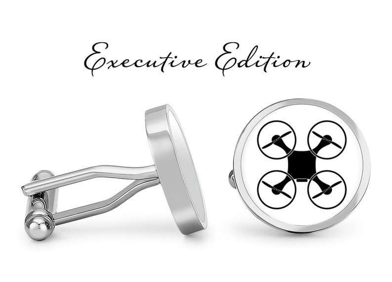 Op de afbeelding: Een paar zilveren manchetknopen met een witte achtergrond en een zwart drone-silhouet. De manchetknopen zijn gelabeld "Executive Edition".