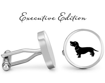 May include: Silver cufflinks with a white background and a black silhouette of a dachshund dog. The cufflinks are labeled "Executive Edition".
