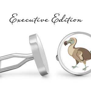 Könnte beinhalten: Silberne Manschettenknöpfe mit weißem Hintergrund und einer Illustration eines braunen und blauen Dodos. Die Manschettenknöpfe sind mit "Executive Edition" beschriftet.