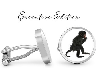 May include: Silver cufflinks with a round, white background featuring a black monkey sitting on its haunches. The text "Executive Edition" is written above the cufflinks.