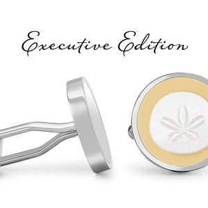 May include: A pair of silver cufflinks with a white and yellow sand dollar design. The cufflinks are labeled "Executive Edition".