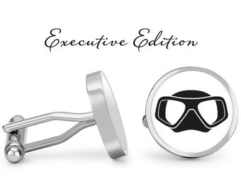 May include: A pair of silver cufflinks with a white background and a black scuba mask design. The cufflinks are labeled "Executive Edition".