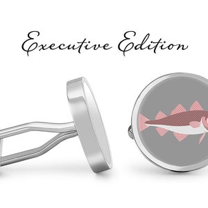 May include: Silver cufflinks with a round, gray background and a pink and white fish illustration. The text "Executive Edition" is written above the cufflinks.