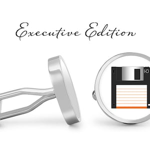 Może przedstawiać: Para srebrnych spinek do mankietów z czarno-białym wzorem dyskietki. Spinki do mankietów są oznaczone jako "Executive Edition".