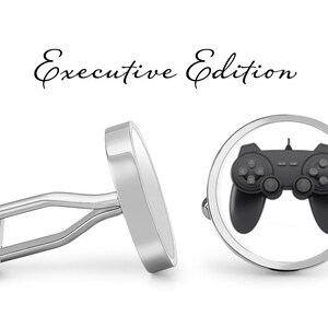 May include: A pair of silver cufflinks with a black video game controller design. The cufflinks are labeled "Executive Edition".
