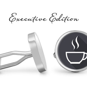 Könnte beinhalten: Silberne Manschettenknöpfe mit einem schwarz-weißen Kaffeetassen-Design. Die Manschettenknöpfe sind rund und das Design befindet sich auf der Vorderseite. Der Text "Executive Edition" steht über den Manschettenknöpfen.