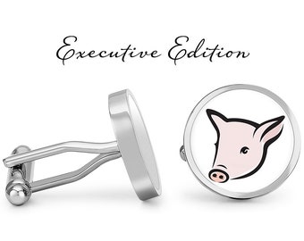 May include: Silver cufflinks with a white background and a cartoon pig face in pink. The cufflinks are labeled "Executive Edition".