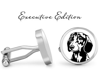 May include: A pair of silver cufflinks with a black and white silhouette of a dachshund dog on one cufflink. The cufflinks are labeled "Executive Edition".