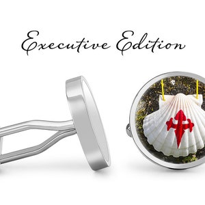 May include: Silver cufflinks with a round image of a white scallop shell with a red cross on it. The text "Executive Edition" is above the cufflinks.