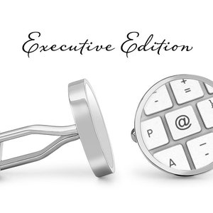 May include: Silver cufflinks with a round design featuring a white computer keyboard with the @ symbol highlighted. The cufflinks are labeled "Executive Edition".
