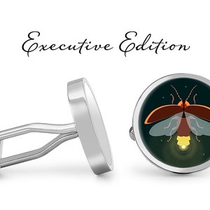 May include: Silver cufflinks with a round, dark green background featuring a stylized illustration of a firefly with orange and yellow accents. The text "Executive Edition" is written above the cufflinks.