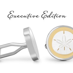 May include: Silver cufflinks with a sand dollar design. The cufflinks have a white sand dollar on a light yellow background, with the words "Executive Edition" in script.