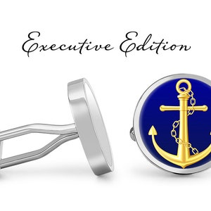 Può includere: Un paio di gemelli d'argento con un design a forma di ancora dorata su sfondo blu. I gemelli sono etichettati "Executive Edition".
