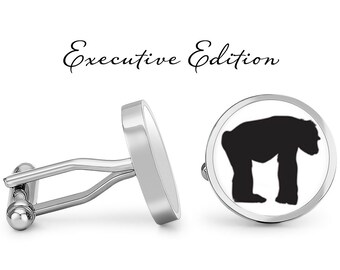 May include: A pair of silver cufflinks with a black silhouette of a chimpanzee on one cufflink. The cufflinks are labeled "Executive Edition".