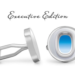 Könnte beinhalten: Silberne Manschettenknöpfe mit rundem Design. Ein Manschettenknopf hat einen weißen Hintergrund mit einem blauen Flugzeugfenster. Der andere Manschettenknopf ist aus massivem Silber. Der Text "Executive Edition" steht über den Manschettenknöpfen.