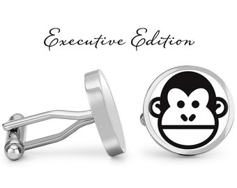 May include: A pair of silver cufflinks with a black and white monkey face design. The cufflinks are round and have a polished finish. The text "Executive Edition" is written above the cufflinks.