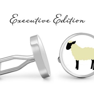 Pode incluir: Abotoaduras de prata com fundo branco e uma silhueta preta de uma ovelha com um casaco de lã amarelo claro. As abotoaduras são etiquetadas como "Executive Edition".