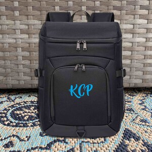 May include: Black backpack with a blue embroidered monogram "KCP" on the front.