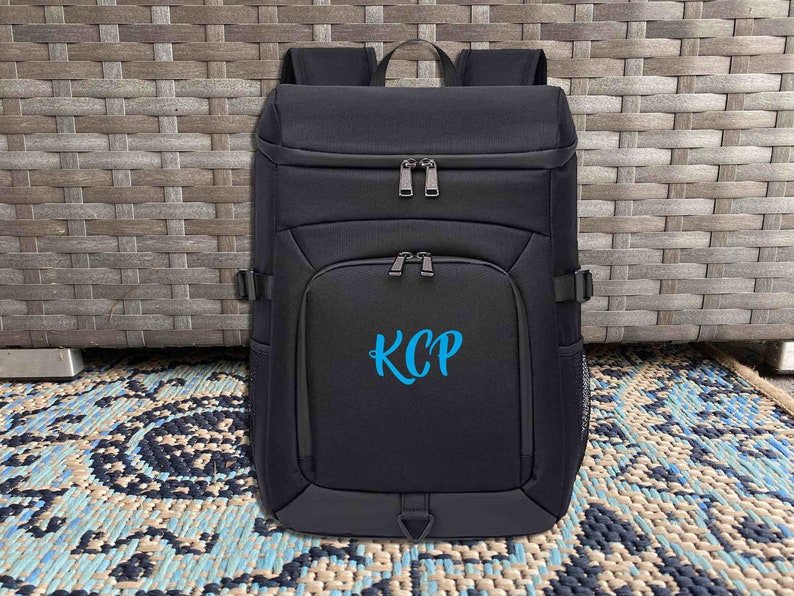 May include: Black backpack with a blue embroidered monogram "KCP" on the front.