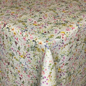 Puede incluir: Un mantel blanco con un patrón floral que presenta una variedad de flores rosas, amarillas y azules. El mantel tiene un sutil efecto acuarela y es perfecto para una mesa de primavera o verano.