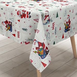 Op de afbeelding: Witte tafelkleed met een feestelijk kerstontwerp met kerstman, sneeuwpoppen en kerstboom. Het tafelkleed heeft een rood-wit kleurenschema en bevat het woord "Hoot!" dat herhaald wordt over de hele oppervlakte.