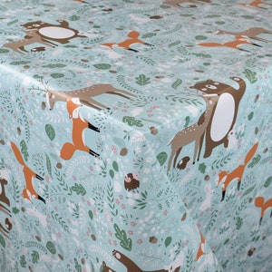 Könnte beinhalten: Eine hellblaue Tischdecke mit einem Waldtier-Druck. Das Muster zeigt Hirsche, Füchse, Bären und andere Waldtiere. Der Hintergrund ist hellblau mit grünen Blättern und Blumen.