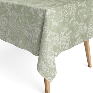 Könnte beinhalten: Eine grüne Tischdecke mit einem weißen Blumenmuster. Die Tischdecke ist aus einem weichen, leinenartigen Stoff gefertigt und hat einen dezenten Glanz.