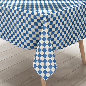 Może przedstawiać: Biało-niebieski obrus w kratkę z rombowym wzorem. Obrus jest rozłożony na drewnianym stole.
