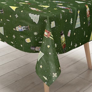 Op de afbeelding: Groene tafelkleed met een herhalend patroon van notenkrakersoldaten, kerstboom, sterren en sneeuwvlokken.
