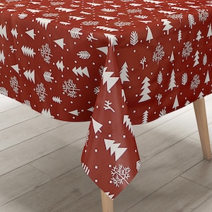 Peut inclure: Nappe rouge avec un motif d'arbre de Noël blanc. La nappe est posée sur une table en bois.