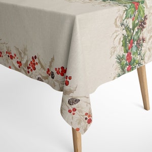 Könnte beinhalten: Eine beige Tischdecke mit einem roten und grünen Muster aus Stechpalmenbeeren. Die Tischdecke ist über einen Tisch mit Holzbeinen gelegt.