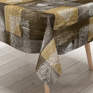 Könnte beinhalten: Eine braune und beige Tischdecke mit Holzmaserung und weißen Blumenmustern. Die Tischdecke ist rechteckig und hat einen Fransenrand.