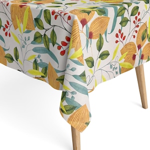 Könnte beinhalten: Eine weiße Tischdecke mit einem floralen Muster mit gelben, orangefarbenen, grünen und roten Blumen und Blättern.