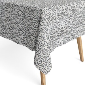 Peut inclure: Une nappe rectangulaire avec un motif répété de feuilles et de vignes grises sur fond blanc. La nappe est drapée sur une table avec des pieds en bois clair. Le tissu a une texture semblable au lin.