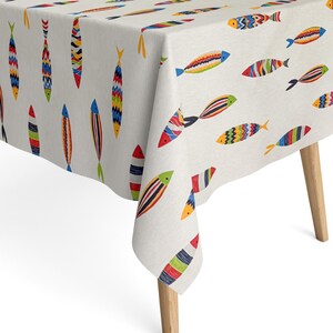 Peut inclure: Une nappe blanche avec un motif de poissons colorés. La nappe est rectangulaire et a un bord frangé. Les poissons sont de toutes les couleurs et de toutes les tailles, et ils sont disposés de manière aléatoire.