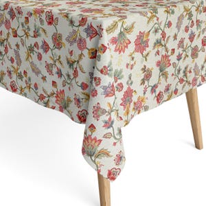 Peut inclure: Une nappe blanche avec un motif floral dans des tons de rouge, rose, jaune et vert. La nappe est faite d'un tissu doux et tissé avec un léger brillant.