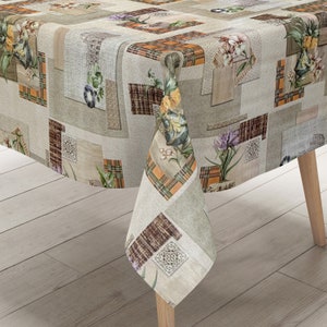 Könnte beinhalten: Eine beige Tischdecke mit Patchwork-Muster, das verschiedene Blumenmuster und ein Karomuster in Orange-, Braun- und Grüntönen zeigt.