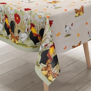 Può includere: Una tovaglia beige con un bordo verde presenta un motivo ripetuto di galli, galline, pulcini e farfalle. I galli sono rossi, gialli e neri. Le galline sono bianche e marroni. I pulcini sono gialli. Le farfalle sono arancioni e marroni.