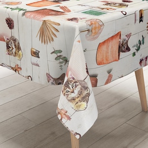 Può includere: Una tovaglia rettangolare con motivo a venature di legno bianco stampata con varie illustrazioni tra cui gattini, cesti intrecciati arancioni, pigne, foglie di palma essiccate e rametti di eucalipto verde disposti in una griglia.