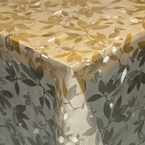 Könnte beinhalten: Eine transparente Vinyl-Tischdecke mit einem Blattgoldmuster. Die Tischdecke hat einen dezenten Glanz und ein zartes Blumenmuster.