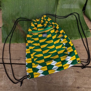 May include: A green and yellow drawstring bag with a small zipped pocket. The bag has a geometric pattern and the text "Ashanti Empire" is printed on the pocket.