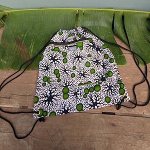 Può includere: Una borsa a cordoncino nera e bianca con un motivo verde e bianco. La borsa ha una tasca con cerniera sul davanti e il testo "Remarkable" stampato sulla linguetta della cerniera.
