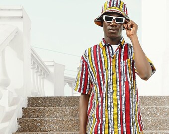 May include: A person wearing a white bucket hat with sunglasses, a striped short-sleeved shirt and matching shorts, and white sneakers with red and blue stripes. The person is walking down a set of stairs.