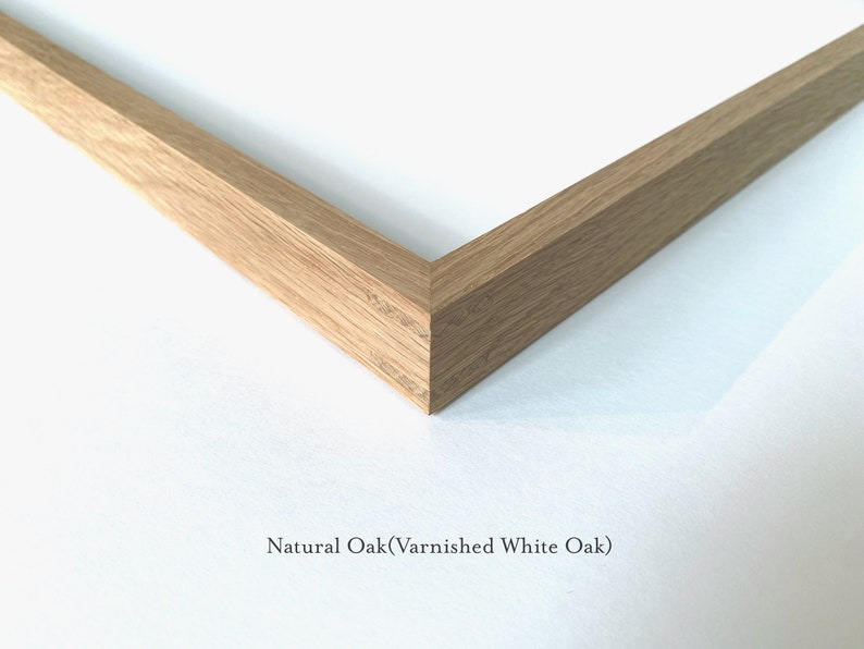 May include: Close-up of a corner of a natural oak picture frame. The frame is made of solid wood and has a smooth finish. The text "Natural Oak (Varnished White Oak)" is visible below the frame.