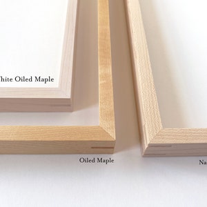May include: Close-up of three wooden picture frames showing different wood finishes. The top frame is white oiled maple, the middle frame is oiled maple, and the bottom frame is natural maple.