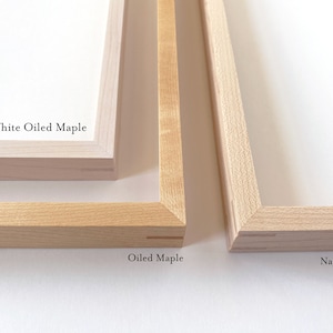 May include: Close-up of three wooden picture frames showing different wood finishes. The top frame is white oiled maple, the middle frame is oiled maple, and the bottom frame is natural maple.