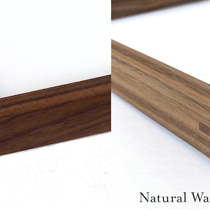 May include: Close-up of two wooden picture frames, one with a natural walnut finish and the other with an oiled walnut finish. Both frames have a simple, rectangular design with mitered corners.