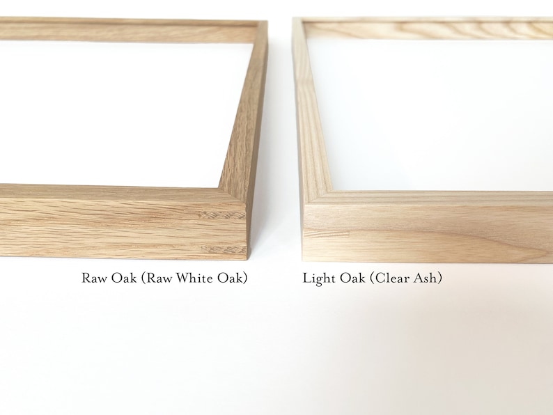 May include: Two wood picture frames, one with a raw oak finish and the other with a light oak finish. The text "Raw Oak (Raw White Oak)" is below the first frame and the text "Light Oak (Clear Ash)" is below the second frame.